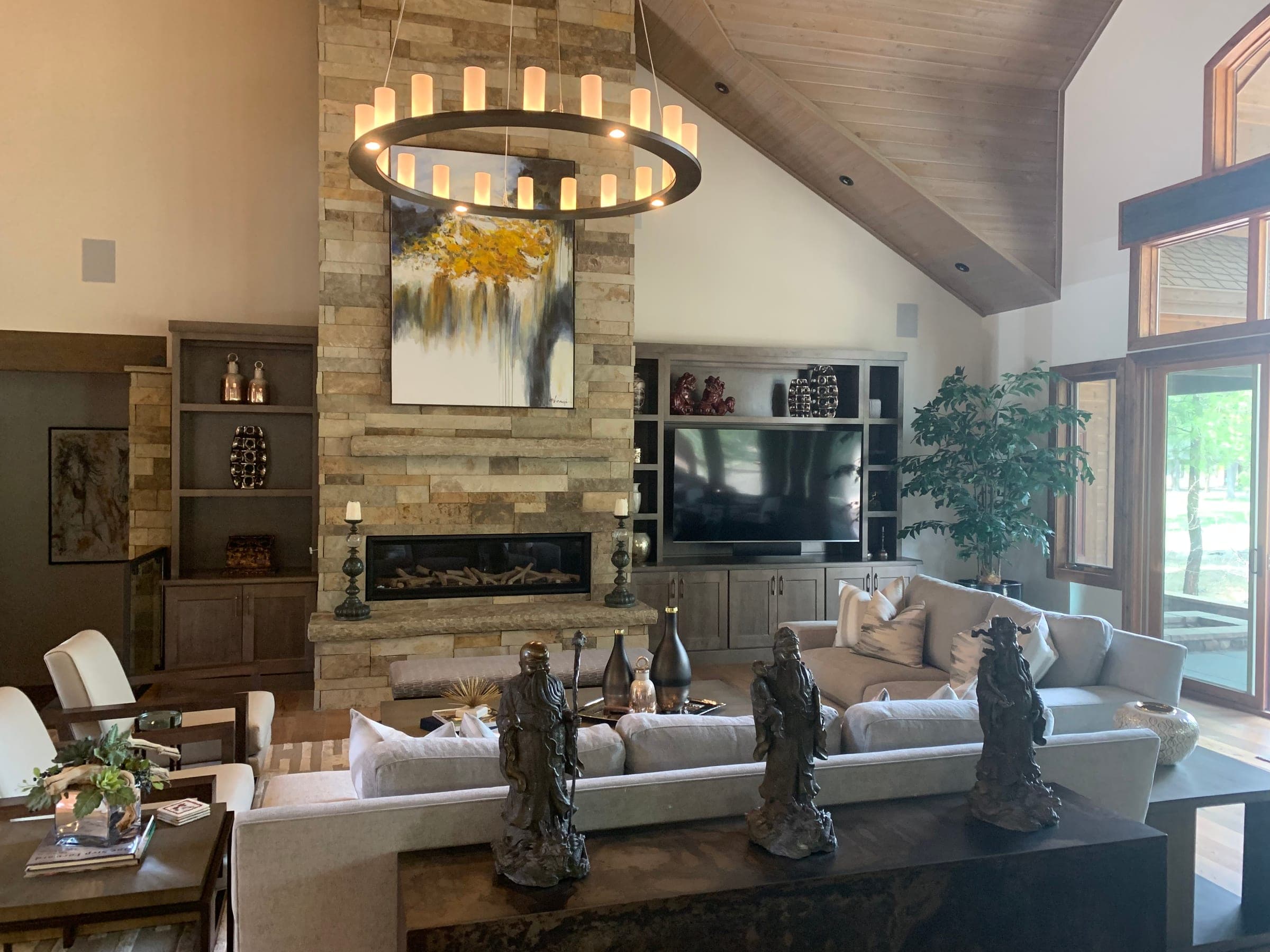 Great room at floor level: stone fireplace, built-in media cabinetry and tall windows under the vaulted ceiling